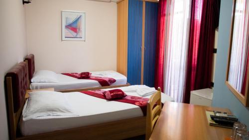 three beds in a room with a desk and a table at Alvero Hotel in Përmet
