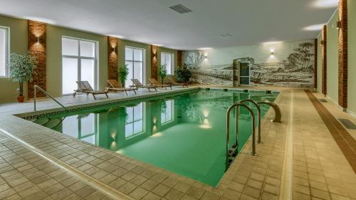 a swimming pool in a hotel with chairs around it at Kadyny Folwark Hotel & SPA in Kadyny