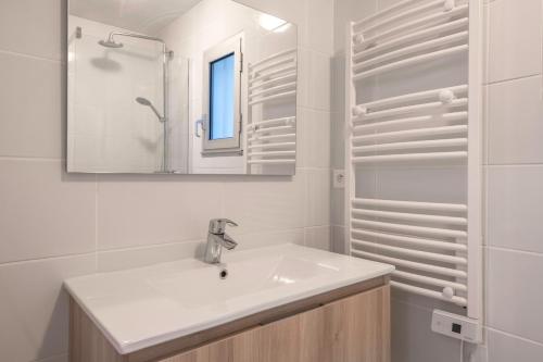 Un baño blanco con lavabo y espejo. en Vacances tout confort à Sarzeau, en Sarzeau