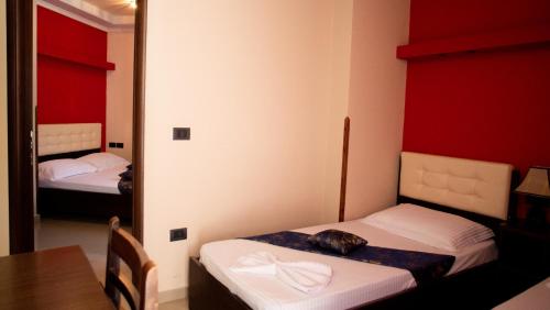 a room with two beds and a table and a mirror at Alvero Hotel in Përmet