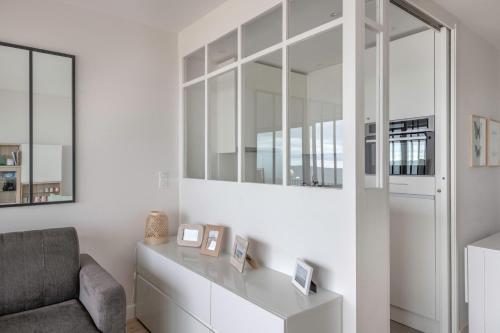 - un salon blanc avec une chaise et un miroir dans l'établissement Vue mer ! Appartement pour 4, à La Baule