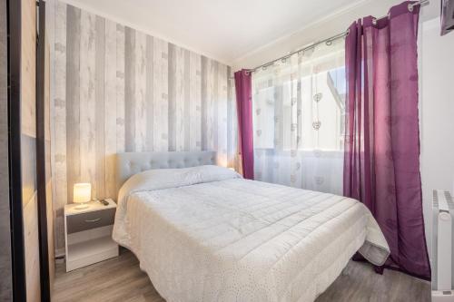 - une chambre avec un lit et une fenêtre avec des rideaux violets dans l'établissement Galene, à Courseulles-sur-Mer