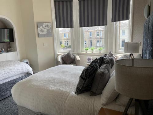 a bedroom with a large bed and two windows at Beechwood Ensuite Guest House in Ayr