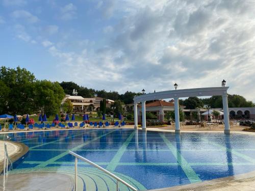 a large swimming pool with blue chairs and a pavilion at Duni Belleville - All Inclusive in Sozopol