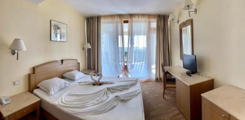 ソゾポルにあるDuni Belleville - All Inclusiveのベッドと机とテレビのある寝室