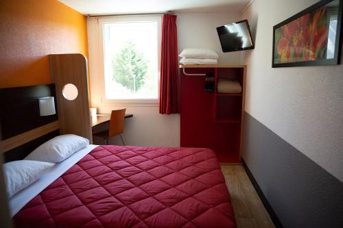 a hotel room with a red bed and a window at Premiere Classe Roissy Aéroport Charles De Gaulle in Roissy-en-France