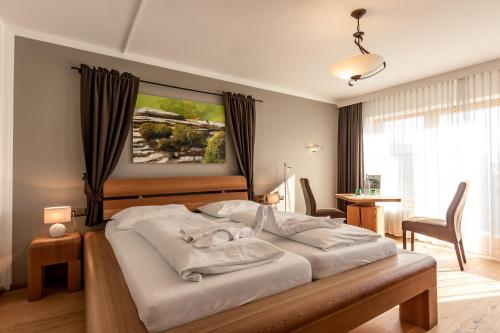 a bedroom with a large bed with white sheets at Hotel Hochfilzer in Ellmau