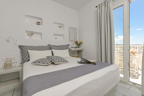 a white bedroom with a large bed and a balcony at Naxos Dream Oniro Studios - Adults Only in Naxos Chora