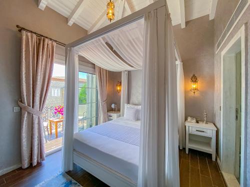 a bedroom with a canopy bed and a window at PROVENCE MANSİON ALAÇATI in Alacati