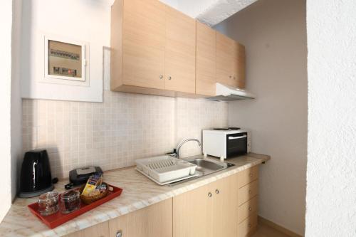 a kitchen with a sink and a microwave at Galini Apartments in Achlia