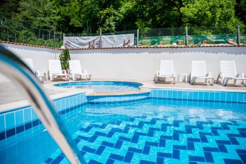 una piscina con sillas blancas y azul en Семеен Хотел Свети Георги en Elena