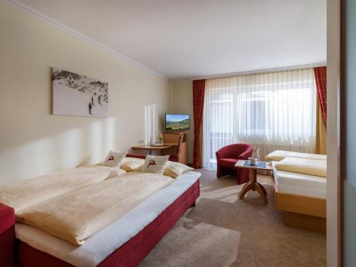 a hotel room with a large bed and a chair at Hotel Glockenstuhl in Westendorf