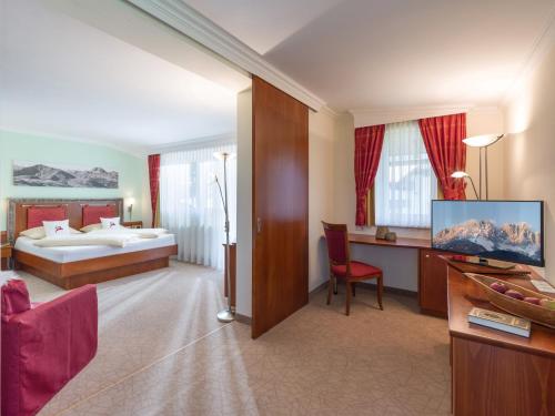 a hotel room with a bed and a desk with a television at Hotel Glockenstuhl in Westendorf