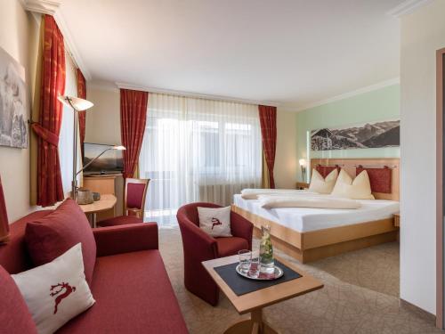 a hotel room with a king sized bed and chairs at Hotel Glockenstuhl in Westendorf
