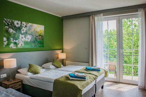 two beds in a room with green walls and a window at Hotel Nowy Zdrój - Centrum Zdrowia i Wypoczynku in Polanica-Zdrój