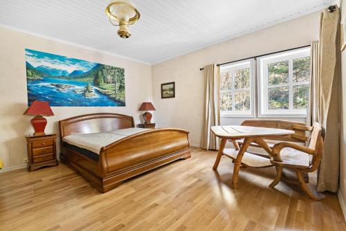 a bedroom with a bed and a table and windows at Utsikten in Kalvåg