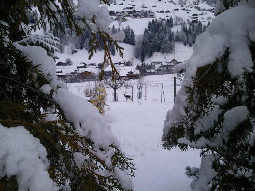 a snow covered yard with a house and animals in the distance at Schweiz ,Lenk Ferienwohnung,Kinderfreundl,Seniorenfreundlich in Lenk