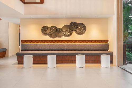 a lobby with a bench and plates on the wall at Cara Hotels Trinidad in Claxton Bay