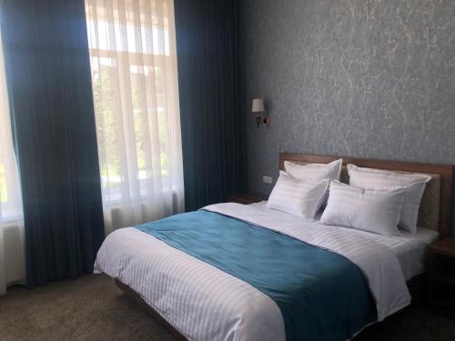 sypialnia z dużym łóżkiem z niebieskimi ścianami i oknem w obiekcie Sabrina Hotel w Samarkandzie