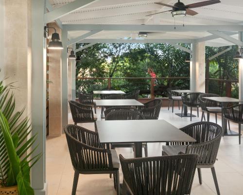 a restaurant with tables and chairs on a patio at Cara Hotels Trinidad in Claxton Bay
