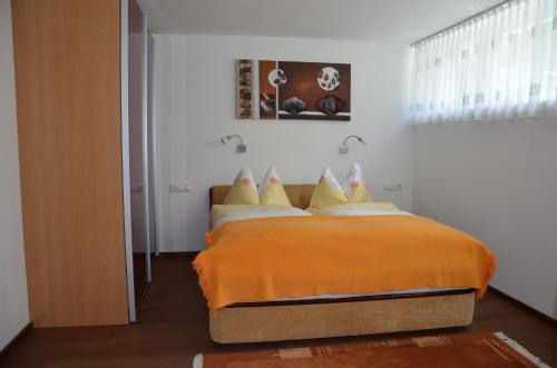 ein Schlafzimmer mit einem Bett mit einer orangefarbenen Decke in der Unterkunft Appartement Nischler in Wald im Pinzgau