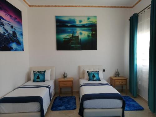 a room with two beds and a painting on the wall at SARA HOUSE NADOR in Nador