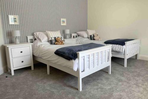 2 letti in una camera da letto con due orsacchiotti sopra di The Loft Cottage a Glastry