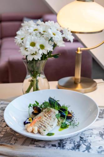 a plate of food on a table with a vase of flowers at Hotel Paryski Art & Business Zakopane - Basen Jacuzzi Sauna Małpi Gaj in Zakopane