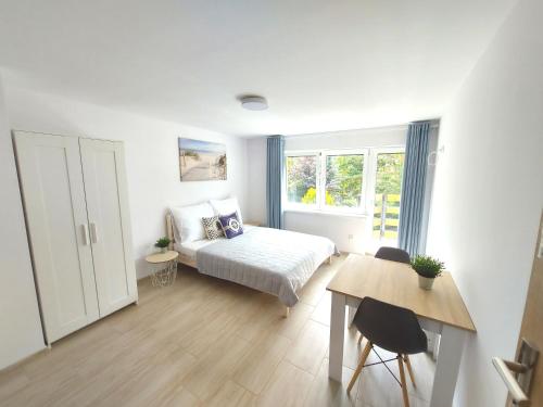um quarto com uma cama, uma mesa e uma janela em Apartamenty Baltic16 em Ustka
