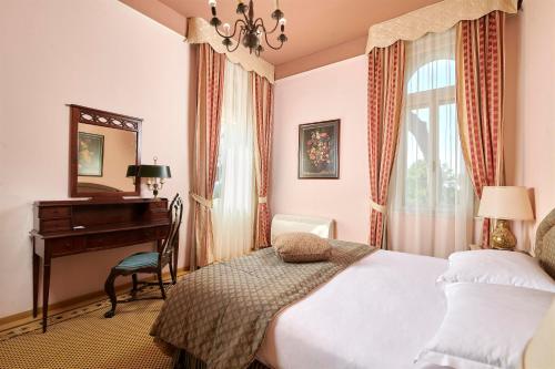 a bedroom with a bed and a desk and a piano at Apartments Bellevue Plava Laguna in Poreč