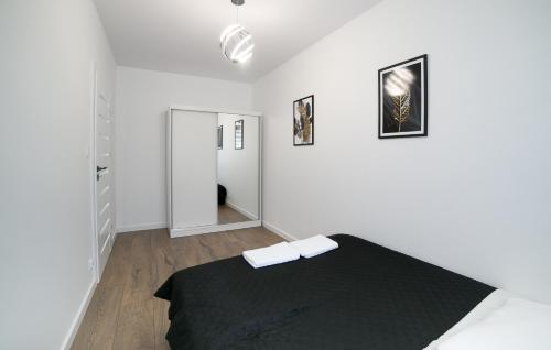 a white bedroom with a black bed and a hallway at Oxygen apartament nr 2 in Mielec