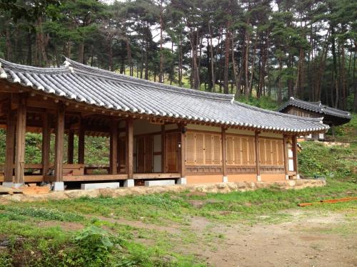 a wooden building with a roof in a forest at Korean Traditional House - Chungnokdang in Boseong