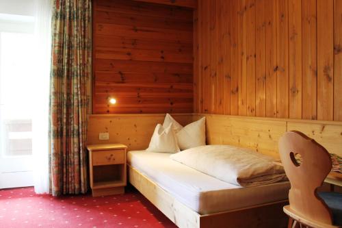ein Schlafzimmer mit einem Bett in einem Holzzimmer in der Unterkunft Albergo Alisander in Kurfar