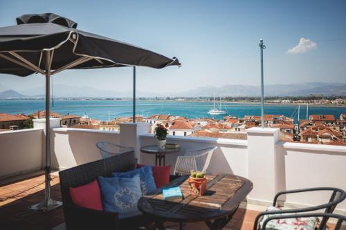 a balcony with an umbrella and a table and chairs at Porto Bello Nafplio in Nafplio
