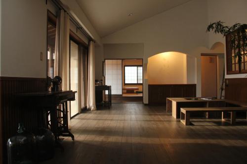 una habitación vacía con una mesa y un banco en ella en 淡路島西海岸の宿 梅木屋 en Sumoto