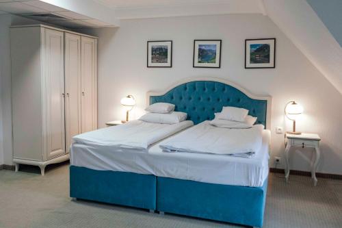 a blue bed in a bedroom with two tables and two lamps at Hotel Paryski Art & Business Zakopane - Basen Jacuzzi Sauna Małpi Gaj in Zakopane