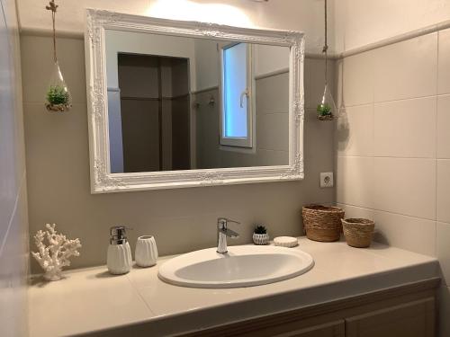 une salle de bain avec un lavabo blanc et un miroir dans l'établissement Villa AZURA, vue panoramique et proche mer à Santa Giulia, piscine chauffée, à Porto-Vecchio