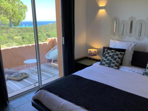 une chambre avec un lit et un balcon avec vue dans l'établissement Villa AZURA, vue panoramique et proche mer à Santa Giulia, piscine chauffée, à Porto-Vecchio