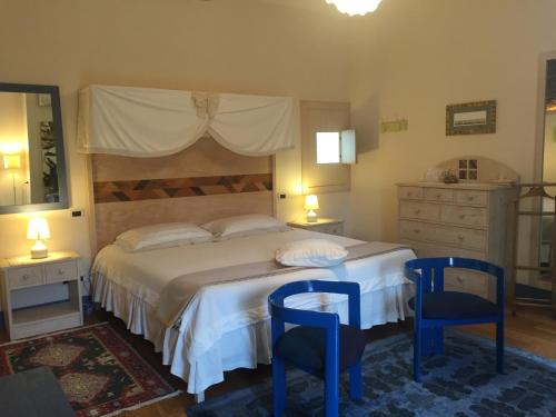 a bedroom with a large bed with two blue chairs at La Vittoria 10 – La Soglia della Val d’Orcia in Chianciano Terme
