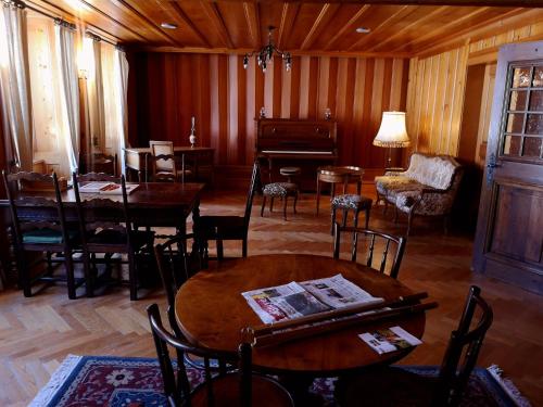 a living room with tables and chairs and a piano at La Fleur de Lys in Gruyères