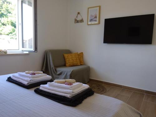 two towels on a bed in a room with a chair at Eco Apartments Kate in Suđurađ