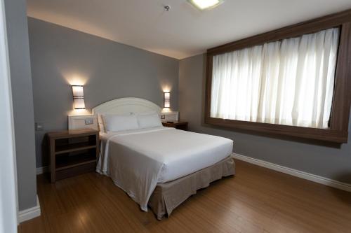 a bedroom with a white bed and a window at Master Porto Alegre Hotel - Av Carlos Gomes, Próximo ao Consulado Americano in Porto Alegre
