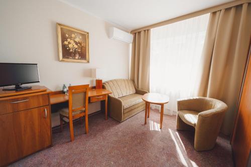 a hotel room with a desk and a tv and a chair at Elita Hotel & Restauracja in Iwonicz-Zdrój