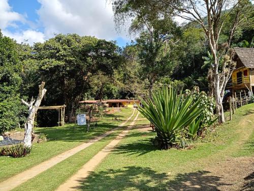 un chemin de terre traversant un parc arboré et une maison dans l'établissement Eco Parque Cachoeira Moxafongo, à Santa Leopoldina