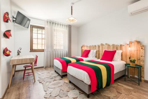 a bedroom with two beds and a desk and a television at Estrela de Montesinho in Bragança