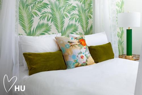 1 cama blanca con almohadas y papel pintado tropical en We Love HU en Hull