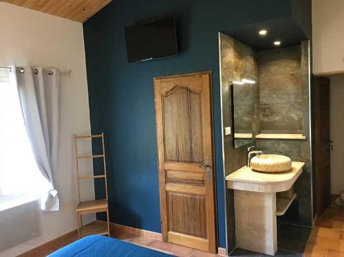 a bathroom with a sink and a tv on the wall at Ferme Para Lou in Sainte-Croix-de-Verdon