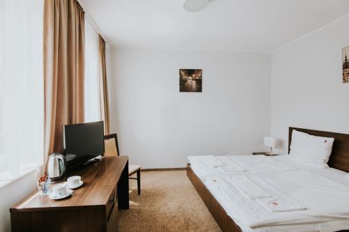 a hotel room with a bed and a desk with a tv at Dworek Pani Walewska in Gdańsk-Rębiechowo