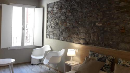 a bedroom with white chairs and a stone wall at Santa Marta Rooms - Vernazza in Vernazza