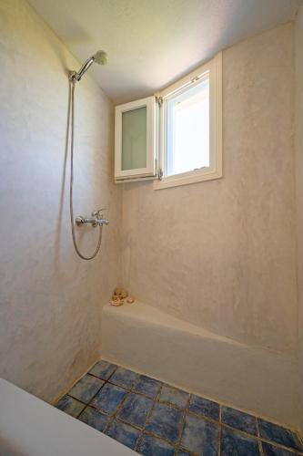a bathroom with a tub and a window and a shower at Molos Sea View House - Paros Greece in Molos Parou
